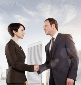 Business woman and business man shaking hands outdoors --- Image by © Matt Bird/Corbis